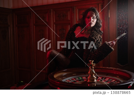 A beautiful brunette in a black dress at the casino roulette wheel. A beautiful brunette in a black dress at the casino roulette wheel. 138878665