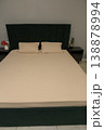 Modern bedroom with green upholstered headboard and beige bedding 138878994
