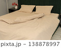 Cozy bedroom with unmade bed and decorative flowers on nightstand 138878997