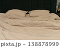 Cozy beige bedding with two pillows on a green upholstered headboard 138878999