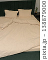 Neatly made bed with beige bedding and green upholstered headboard 138879000