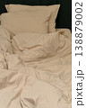 Soft beige bedding with pillows arranged on a dark green headboard 138879002
