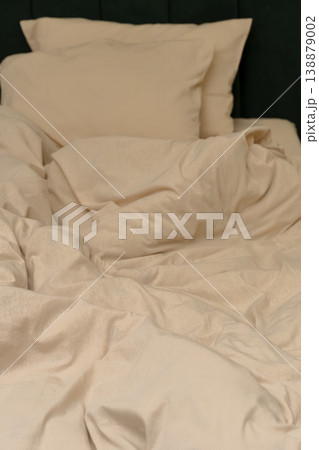 Soft beige bedding with pillows arranged on a dark green headboard Soft beige bedding with pillows arranged on a dark green headboard 138879002