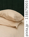 Soft beige pillows stacked on a bed with a green upholstered headboard 138879003