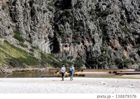 Tourists walk towards a huge rock in a picturesque gorge. Tourists walk towards a huge rock in a picturesque gorge. 138879376