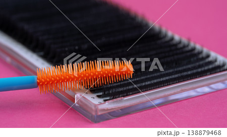 Macro close-up of an orange mascara wand on eyelash extension tray over pink background Macro close-up of an orange mascara wand on eyelash extension tray over pink background 138879468