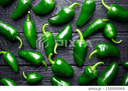 Multiple jalapeno peppers scattered on dark stone surface 138880068