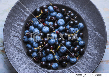 Top view of berry assortment in black plate on textured background 138880102