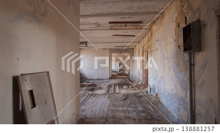 Long Peeling Corridor In Exclusion Zone, Cracked Plaster Walls, Scattered Rubble And Exposed Wiring, Dim Long Peeling Corridor In Exclusion Zone, Cracked Plaster Walls, Scattered Rubble And Exposed Wiring, Dim 138881257