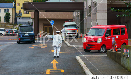 Muroran, Hokkaido, Japan - Oct 4 2024, panoramic view of the street where there is a traffic controller pointing the direction of a red kei car entering the road, at daytime, Muroran, Japan Muroran, Hokkaido, Japan - Oct 4 2024, panoramic view of the street where there is a traffic controller pointing the direction of a red kei car entering the road, at daytime, Muroran, Japan 138881953