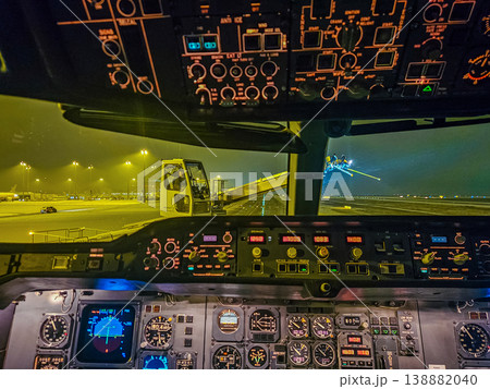 The illuminated flight deck of an airplane preparing for takeoff. A de-icing vehicle is visible on the wet tarmac through the cockpit window. High quality photo The illuminated flight deck of an airplane preparing for takeoff. A de-icing vehicle is visible on the wet tarmac through the cockpit window. High quality photo 138882040