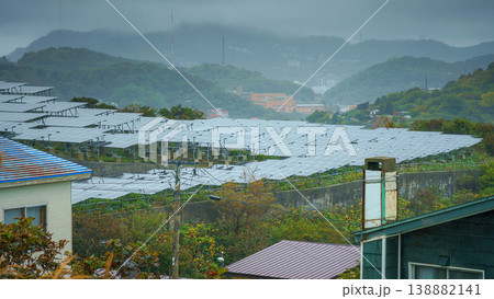 Muroran, Hokkaido, Japan - Oct 4 2024, panoramic view of a solar power plant in a clearing, with mountains and houses covered in fog in background, without people, in cloudy weather, Muroran, Japan 138882141