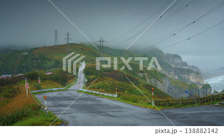 Muroran, Hokkaido, Japan - Oct 4 2024, panoramic view of road running along slopes of mountains, along it there are power lines, in background everything is covered with fog, in cloudy, Muroran, Japan Muroran, Hokkaido, Japan - Oct 4 2024, panoramic view of road running along slopes of mountains, along it there are power lines, in background everything is covered with fog, in cloudy, Muroran, Japan 138882142