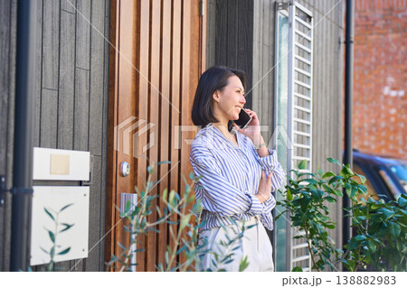 住宅の玄関前で電話をする日本人女性の横顔 住宅の玄関前で電話をする日本人女性の横顔 138882983
