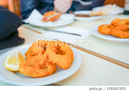 バルセロナ市内のレストランでシェアされたテーブル上のカリッと揚がったイカリングのフライ 138883303