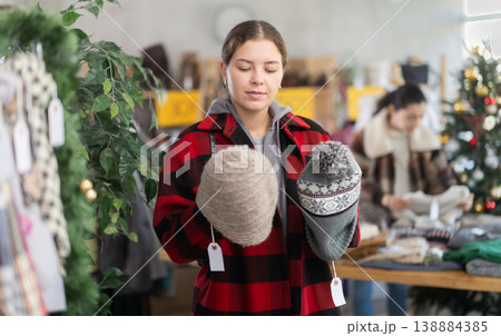 Woman in a clothing store choosing a winter hat in a store Woman in a clothing store choosing a winter hat in a store 138884385