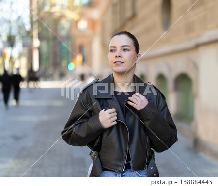 Young woman walks along city street 138884445