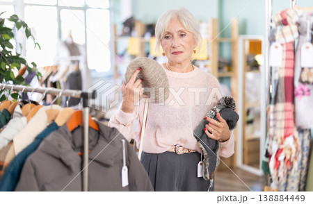 Mature woman choosing a winter hat Mature woman choosing a winter hat 138884449
