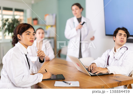 Interested medic student or doctor sitting at table discussing ideas and watching presentation during meeting in office 138884459