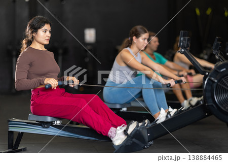Sportive Latina girl training with rowing machine in sports hall 138884465