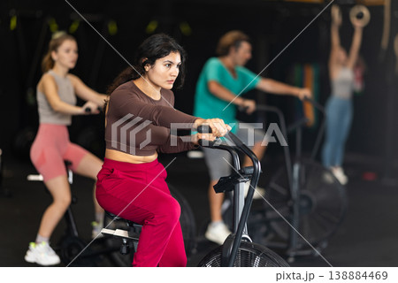 Latina woman doing exercises on air bike in Crossfit gym Latina woman doing exercises on air bike in Crossfit gym 138884469