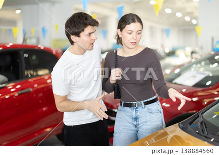 Young couple in a car dealership chooses a car Young couple in a car dealership chooses a car 138884560