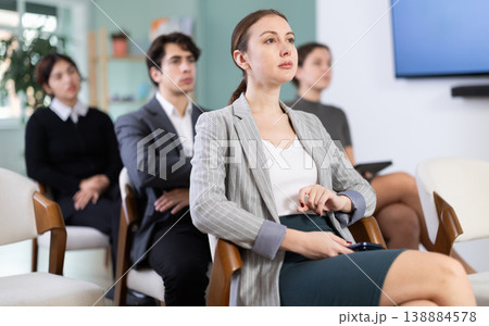 Diligent woman student with group of other students listening lecture at lesson in university 138884578