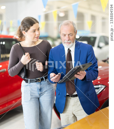 Elderly auto salesman advises a client, answering her questions Elderly auto salesman advises a client, answering her questions 138884594