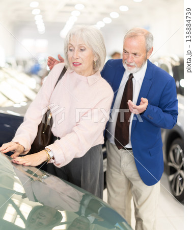 Elderly couple is standing in a car dealership Elderly couple is standing in a car dealership 138884739