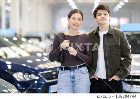 Young couple in a car dealership chooses a car Young couple in a car dealership chooses a car 138884744