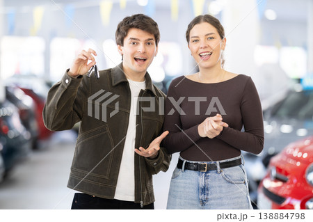 Young couple holding keys to new car in dealership 138884798