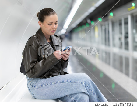 Young woman with phone sitting at metro station 138884833