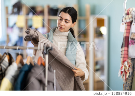 Girl chooses fashionable trousers in clothing store Girl chooses fashionable trousers in clothing store 138884916