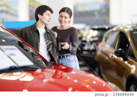 Couple discussing new car inside dealership showroom, lifestyle and transport concept of auto sales 138884930