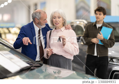 Elderly couple with new car keys, salesman with contract 138884931