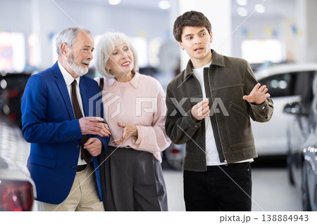 Young salesman selling car to mature couple at dealership 138884943
