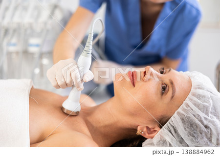 Young woman undergoing ultrasound cosmetic treatment on chest and neck area Young woman undergoing ultrasound cosmetic treatment on chest and neck area 138884962