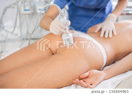Aesthetician administering ice hammer therapy on female client buttocks Aesthetician administering ice hammer therapy on female client buttocks 138884963