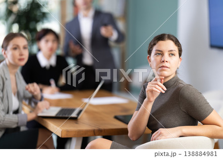 Interested malaysian girl office worker sitting at table with group of people and watching presentation during business meeting in office Interested malaysian girl office worker sitting at table with group of people and watching presentation during business meeting in office 138884981