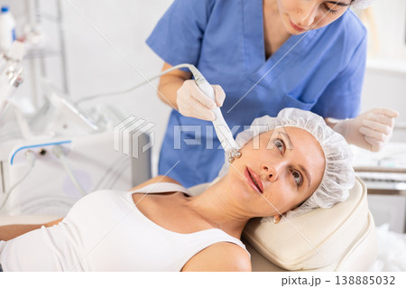 Young woman cosmetologist doing microcurrent procedure to young woman Young woman cosmetologist doing microcurrent procedure to young woman 138885032