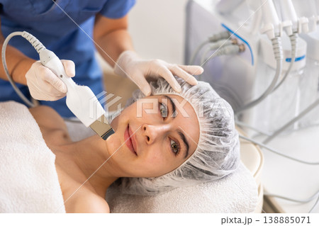 Young woman cosmetologist doing exfoliation procedure to young woman Young woman cosmetologist doing exfoliation procedure to young woman 138885071