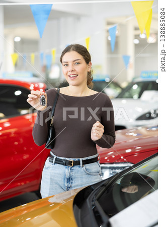 Happy cheerful girl bought car - portrait of joyful girl with car keys in car dealership 138885084