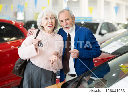 Joyful elderly couple stands near the car with a set of keys after purchase. 138885088