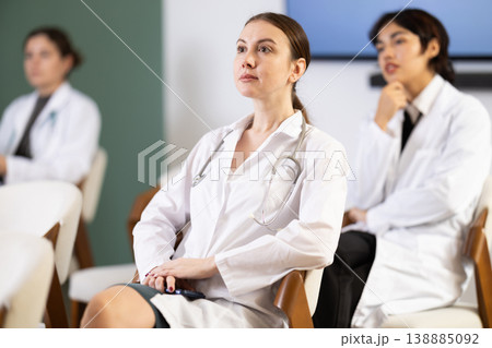 Young female doctor listening and taking notes in lecture hall Young female doctor listening and taking notes in lecture hall 138885092