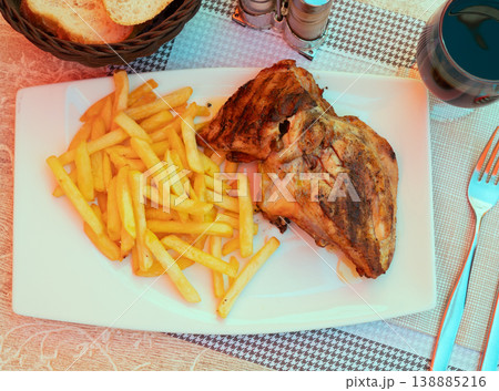 Baked chicken leg served on plate with side dish of fried potatoes Baked chicken leg served on plate with side dish of fried potatoes 138885216
