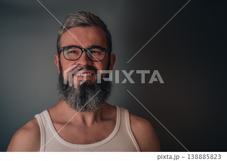 Man with beard and glasses smiling against a plain background Man with beard and glasses smiling against a plain background 138885823