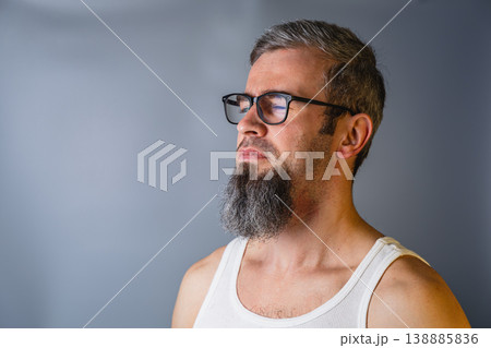 Man with beard and glasses stands in front of gray background Man with beard and glasses stands in front of gray background 138885836