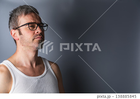 Man wearing glasses looks to the side against a plain backdrop Man wearing glasses looks to the side against a plain backdrop 138885845