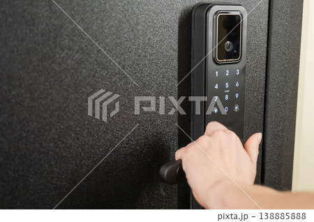 A woman opens a modern smart door lock with a digital keypad and biometric fingerprint access. A woman opens a modern smart door lock with a digital keypad and biometric fingerprint access. 138885888