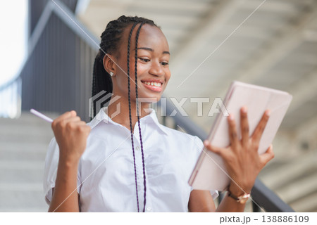 Young African business woman celebrating success while looking at tablet, concept of achievement, winning result, online business growth, motivation and modern digital productivity. Young African business woman celebrating success while looking at tablet, concept of achievement, winning result, online business growth, motivation and modern digital productivity. 138886109